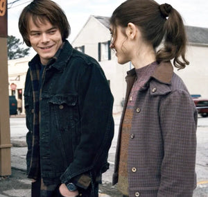 A man and woman stand on a sidewalk, with the woman wearing the Zing Apparel Stranger Things S01 Nancy Wheeler Purple Jacket.